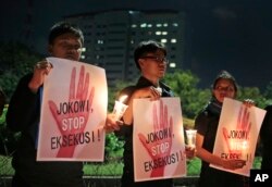 Para aktivis membawa poster bertuliskan “Jokowi, stop eksekusi!” dalam acara doa bersama menentang hukuman mati di luar istana kepresidenan di Jakarta, 28 Juli 2016.