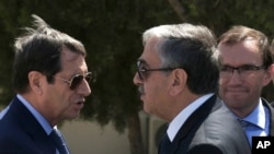 FILE - Cypriot President Nicos Anastasiades, left, and breakaway Turkish Cypriot leader Mustafa Akinci, right, talk at the disused Nicosia airport inside a United Nations controlled buffer zone in this divided island of Cyprus, Sept. 14, 2016. 