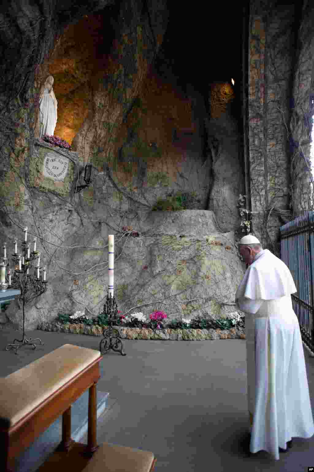 Paus Fransiskus berdoa di depan patung Perawan Maria di Vatikan.