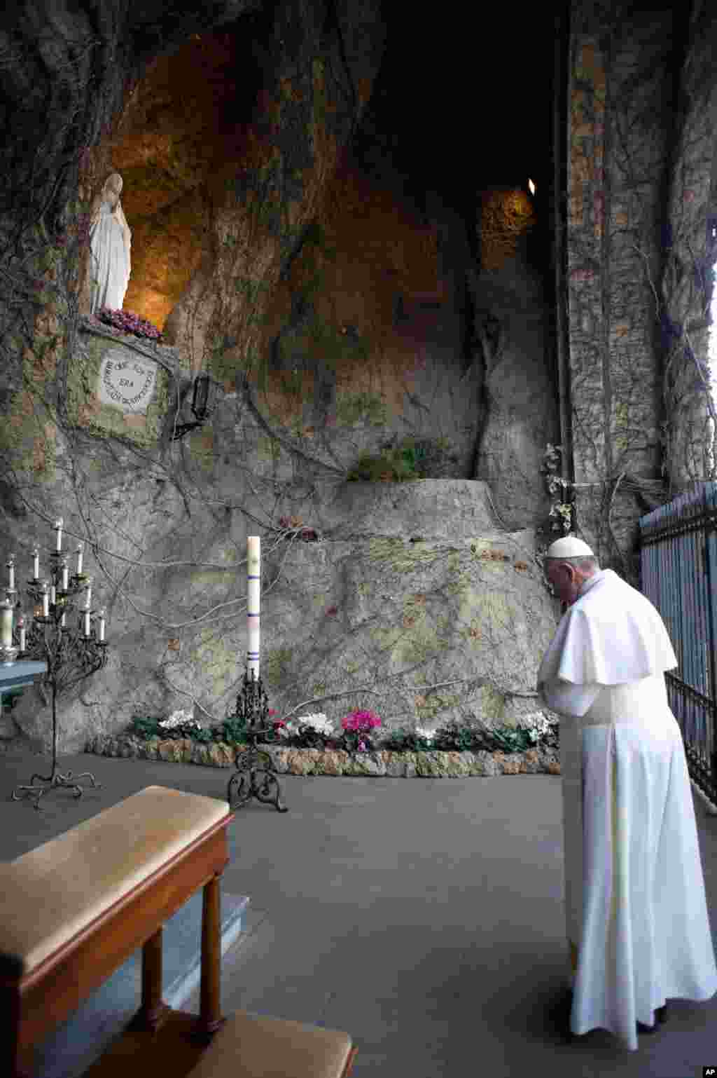 Pope Francis prays in front of a statue of the Virgin Mary at the Vatican.