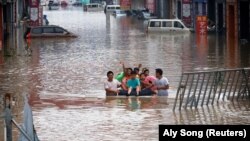 Children sit on a makeshift raft on a flooded road following heavy rainfall in Zhengzhou, Henan province, China July 22, 2021. 