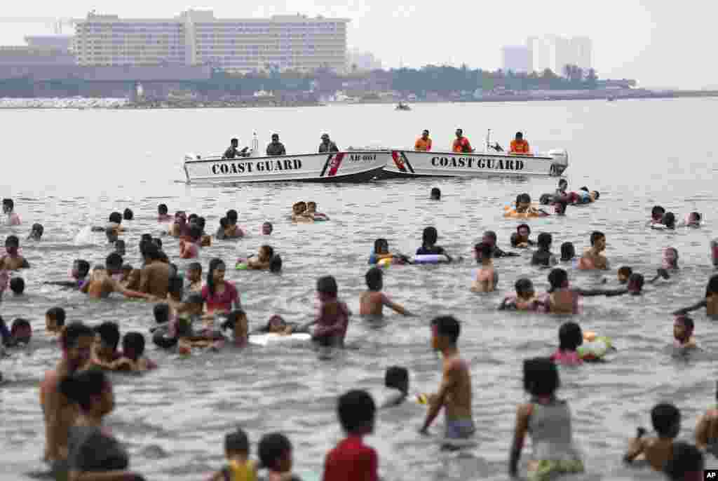 Philippine Coast Guard personnel stay beside people swimming just outside the U.S. Embassy as they celebrate Easter Sunday, Manila, Philippines, April 20, 2014. 