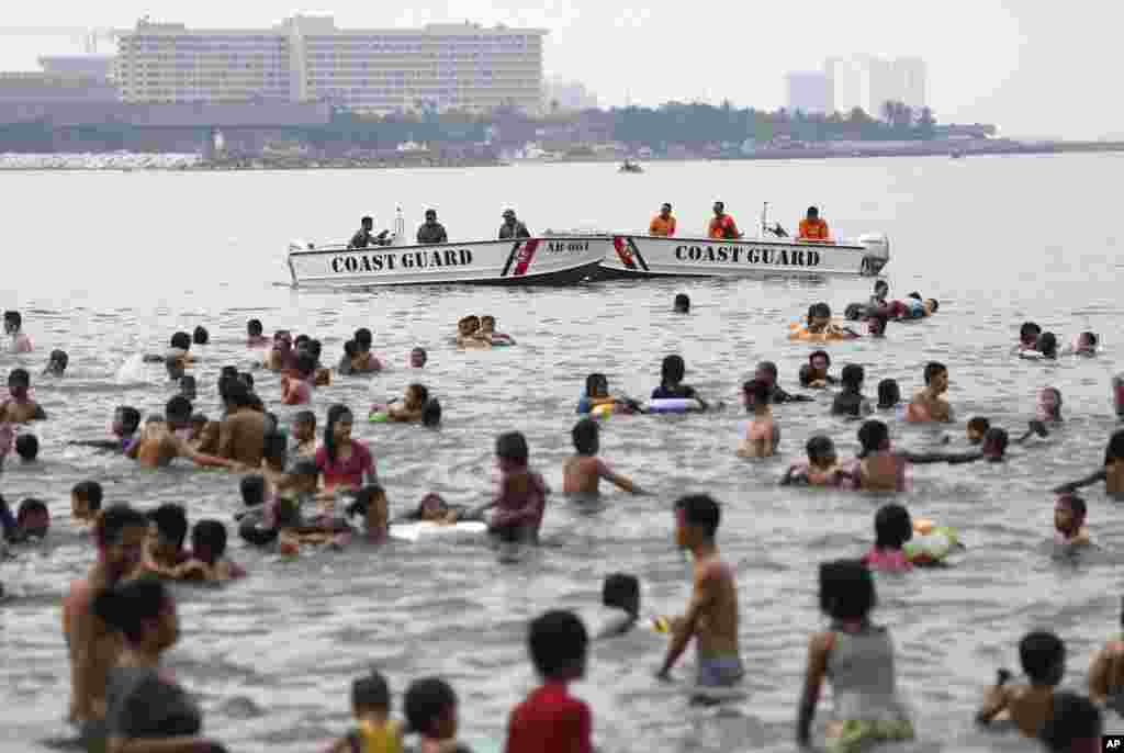 Penjaga pantai Filipina berjaga-jaga di luar Kedutaan Besar AS dekat orang-orang yang berenang pada hari libur Paskah di Manila. &nbsp;(AP/Aaron Favila)