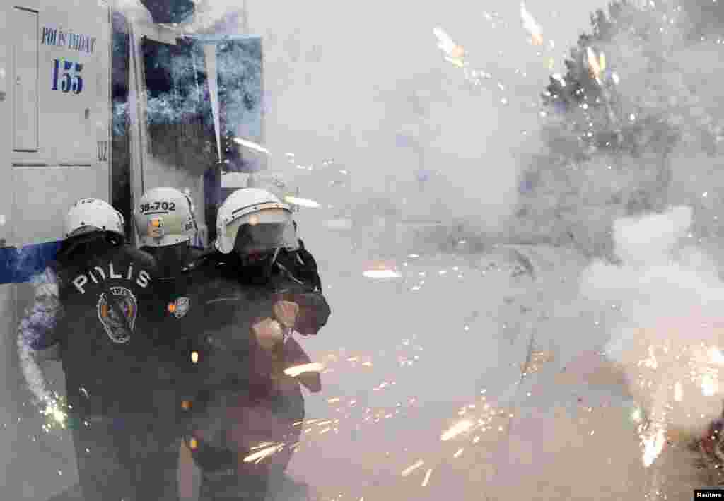 Turkish riot police take cover as protestors use fireworks against them during a demonstration against the opening of a new road in Ankara.