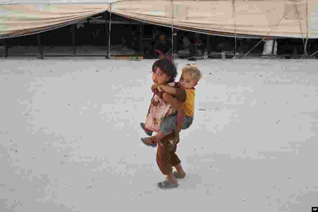 کودک آوره سوری در حالیکه کودکی را بر دوش خود حمل می کند در کمپ آوارگان سوری در شمال شرقی سوریه