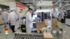 FILE - Employees work on a mobile phone production line during a media tour at a Huawei factory in Dongguan, in China's Guangdong province, March 6, 2019. 