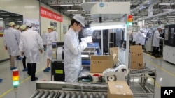 FILE - Employees work on a mobile phone production line during a media tour at a Huawei factory in Dongguan, in China's Guangdong province, March 6, 2019. 