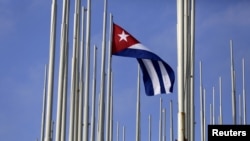 FILE - The Cuban flag flies in front of the U.S. Interests Section, background, in Havana, May 22, 2015. 