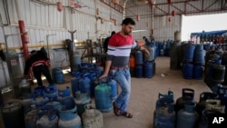 In this Thursday, Jan. 7, 2016 photo, a Palestinian worker carries a gas canister filled only by half, as other bottles wait to be filled at the main gas station in Jebaliya, Gaza Strip. Gas used for heating and cooking in Gaza is in short supply because 