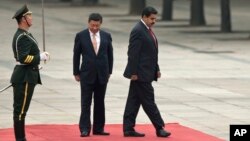 El presidente chino Xi Jinping, centro, y el mandatario venezolano Nicolás Maduro, ajustan el paso durante la revista a la guardia de honor en Beijing.