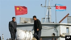 FILE - North Korean men stand on a boat used for trade between China and North Korea on the waterfront at the North Korean town of Sinuiju, opposite the Chinese border city of Dandong, Oct. 11, 2006.