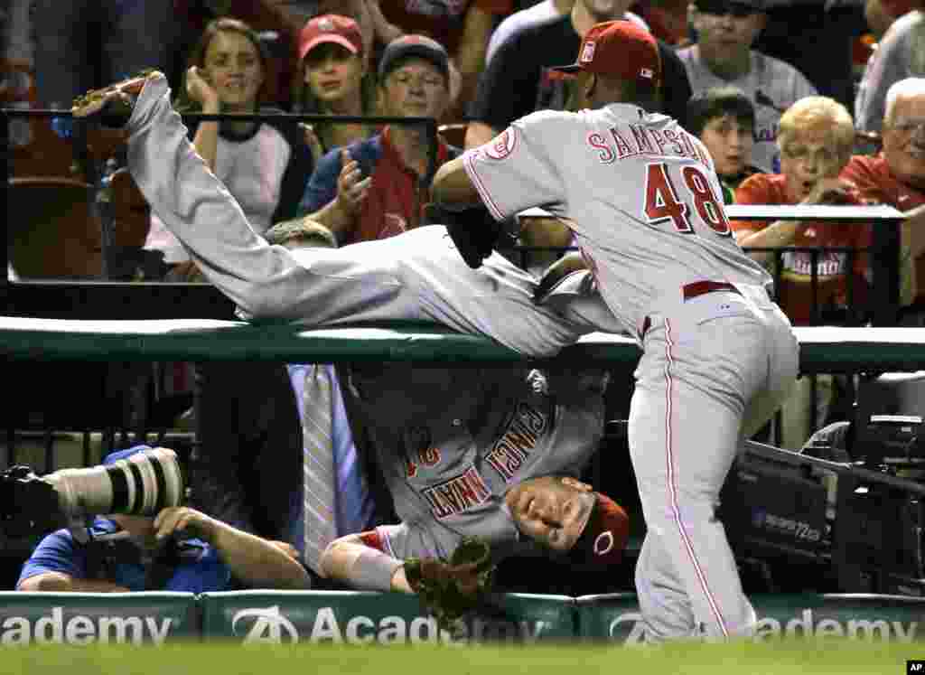 Cincinnati Reds third baseman Todd Frazier, left, is held back from falling further into a photo pit by teammate Keyvius Sampson after catching a foul ball hit by St. Louis Cardinals&#39; Matt Adams for an out during the fourth inning of a baseball game in St. Louis, Missouri, USA, Sept. 22, 2015.