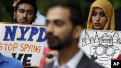 FILE - People hold signs while attending a rally to protest New York Police Department surveillance tactics near police headquarters in New York, Aug. 28, 2013. 