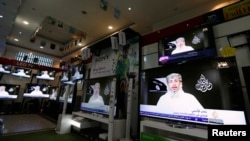 Nasr al-Ansi, a leader of the Yemeni branch of al-Qaida (AQAP), is shown on televisions at a shop, delivering a message in which AQAP claims responsibility for the attack on Charlie Hebdo last week, in Sanaa, Yemen, Jan. 14, 2015.