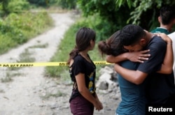 FILE - The friends of two men who were killed in gang violence cry at the crime scene in San Pedro Sula, Honduras, July 24, 2018.