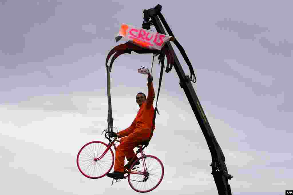 A supporter rides a bike suspended in the air along the road during the 222-km 15th stage of the 101st edition of the Tour de France cycling race between Tallard and Nimes, southern France.