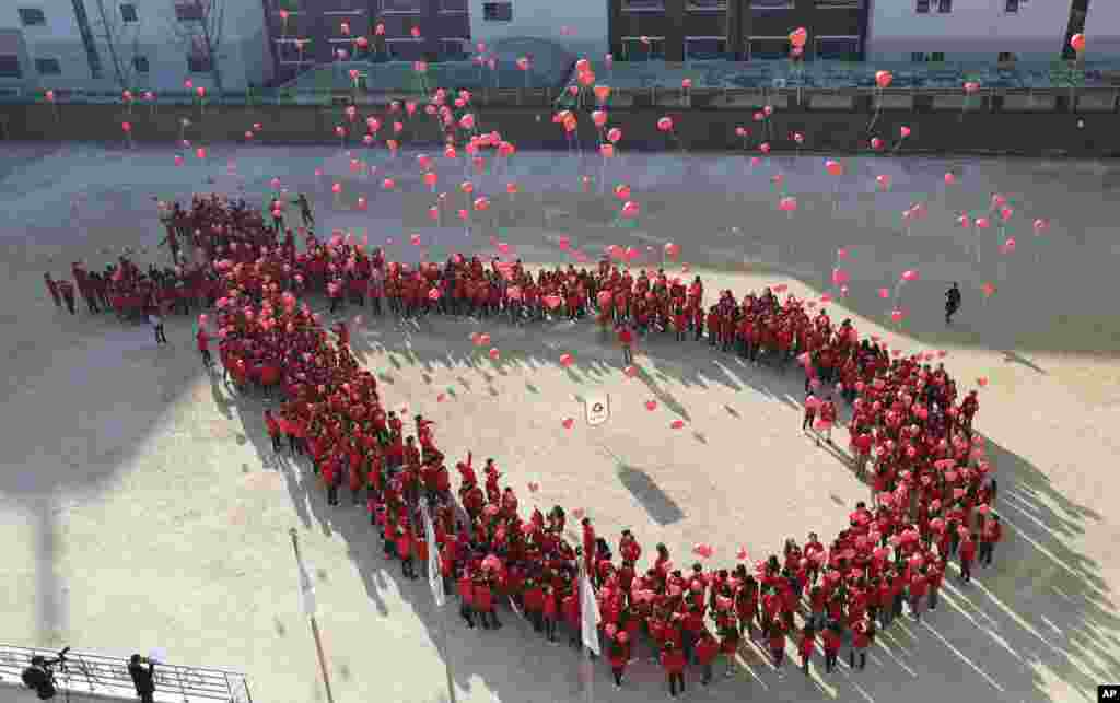 South Korean students make a formation in the shape of the red ribbon, the universal symbol of awareness and support for those living with HIV, as they release balloons during an event to mark the upcoming World AIDS Day in Seoul, Dec. 1, 2016.