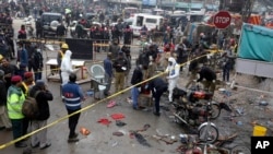 Police officials and investigators examine the site of bomb explosion, in Lahore, Pakistan, Jan. 20, 2022. 