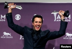 Luke Bryan poses with his awards for entertainer of the year and vocal event of the year at the 48th ACM Awards in Las Vegas, April 7, 2013.