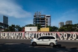 Sebuah mobil melewati tembok pinggir jalan penuh coretan di tengah pandemi COVID-19 di Jakarta, 21 Juni 2021. (Foto: BAY ISMOYO / AFP)