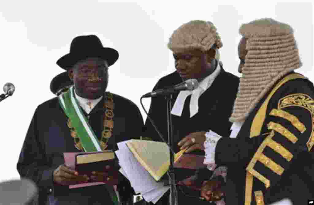 Nigerian President Goodluck Jonathan, left, takes the oath of office before Justice Sunday Olorundanusi, center, and Chief Justice of Nigeria Katsina Alu during his inauguration ceremony at the main parade ground in Nigeria's capital of Abuja Sunday, May 