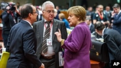 German Chancellor Angela Merkel (R) speaks with French President Francois Hollande (L) during a round table meeting at an EU summit in Brussels, March 15, 2013.