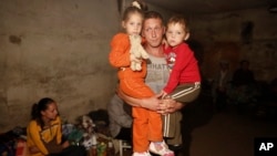 Seorang pria menggendong dua orang anaknya di dalam sebuah basement (ruang bawah tanah) untuk menghindari peperangan di Donetsk, Ukraina timur (foto: dok).