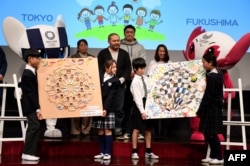 Elementary school students from Fukushima (L) and Tokyo (R) exchange mementos during an event marking 500 days till the Tokyo 2020 Olympic Games in Tokyo, March 12, 2019.