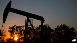 In this Feb. 19, 2015 photo, the sun sets behind an oil well in a field near El Tigre, a town within Venezuela's Hugo Chavez oil belt, formally known as the Orinoco Belt.