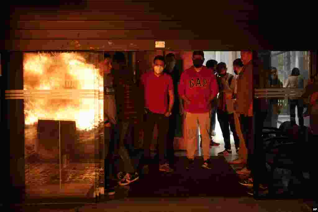 People stay inside a shop as pro-independence activists burn garbage containers during a demonstration in Barcelona to mark 3rd anniversary of failed independence referendum, Spain, Thursday, Oct. 1, 2020.