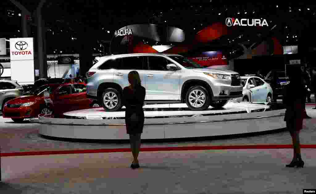 Models stand near vehicles on display at the New York International Auto Show in New York City.