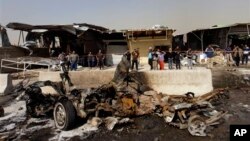 Warga Irak memeriksa lokasi serangan bom mobil di wilayah Ameen timur Baghdad, Irak, Minggu, 17 Februari, 2013. Serangkaian bom mobil meledak dalam waktu hampir bersamaan saat warga setempat berbelanja di sekitar Baghdad di akhir pekan tersebut. (AP Photo / Khalid Mohammed)