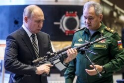 Russian President Vladimir Putin, left, and Russian Defense Minister Sergei Shoigu visit an military exhibition after attending an extended meeting of the Russian Defense Ministry Board at the National Defense Control Center in Moscow, Dec. 21, 2021.