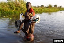 FILE - Children cross a body of water to reach a registration area prior to a food distribution carried out by the United Nations World Food Program (WFP) in Thonyor, Leer state, South Sudan.