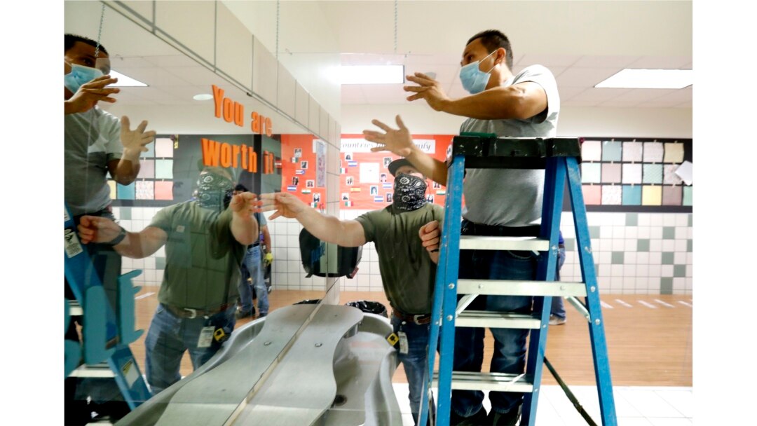 Richardson Independent School District workers Rogelio Ponciano, right, and Matt Attaway install a plexiglass barrier for the sink in the student restroom at Bukhair Elementary School in Dallas, Wednesday, July 15, 2020.