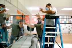 Richardson Independent School District workers Rogelio Ponciano, right, and Matt Attaway install a plexiglass barrier for the sink in the student restroom at Bukhair Elementary School in Dallas, Wednesday, July 15, 2020.