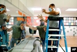 Richardson Independent School District workers Rogelio Ponciano, right, and Matt Attaway install a plexiglass barrier for the sink in the student restroom at Bukhair Elementary School in Dallas, Wednesday, July 15, 2020.