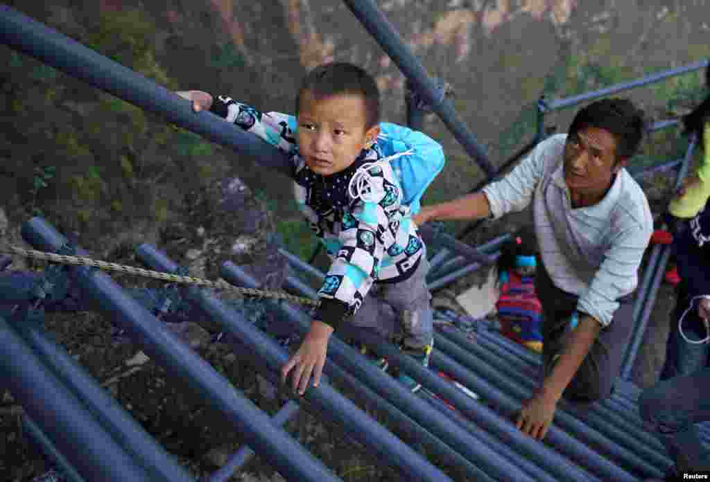 A student from &quot;the cliff village&quot; in Atule&#39;er climbs newly-constructed steel ladders after school to go home for holidays, in Liangshan Sichuan province, China.