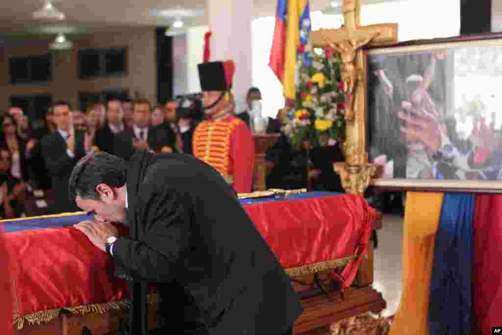 In this photo released by Miraflores Press Office, Iran's President Mahmoud Ahmadinejad kisses the flag-draped coffin of late Venezuela's President Hugo Chavez during the funeral ceremony at the military academy in Caracas, Venezuela, Mar. 8, 2013.
