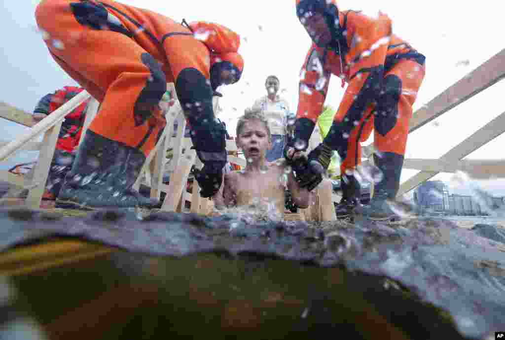 Rescue workers dip a boy in the icy water in the Neva River during a traditional Epiphany celebration in St. Petersburg, Russia.