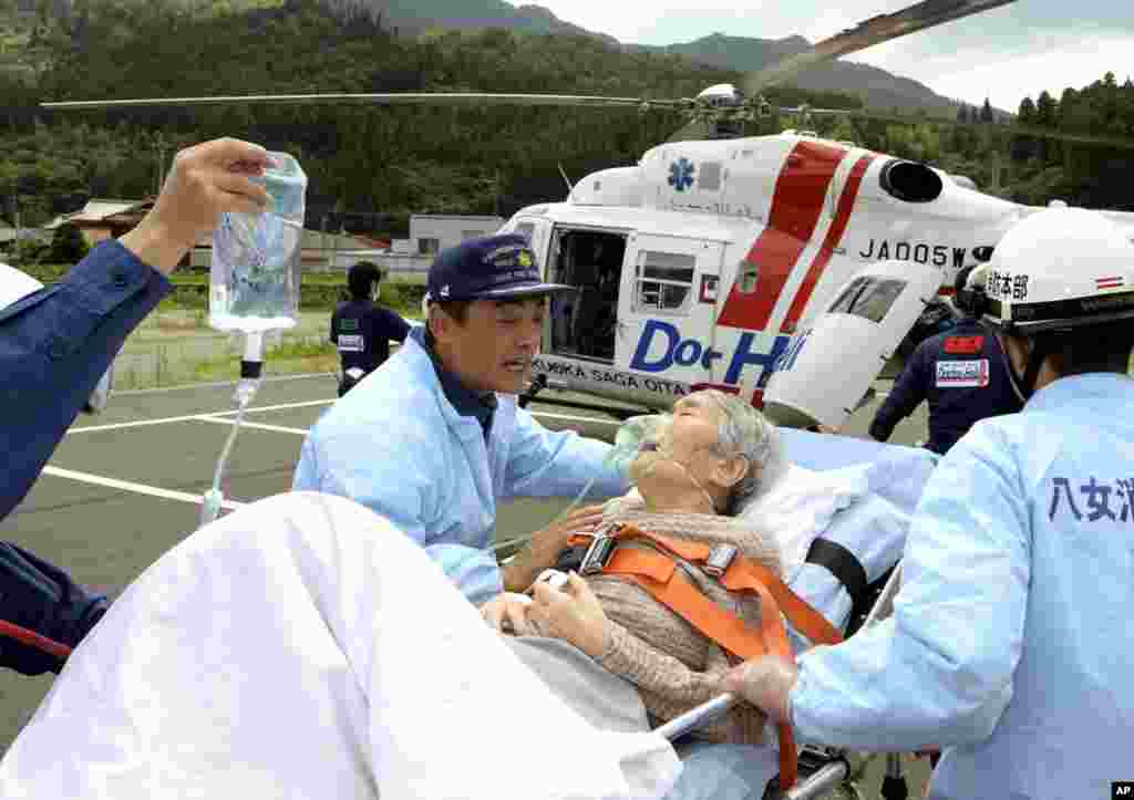 Petugas mengangkut seorang perempuan lansia dengan tandu untuk dibawa dengan helikopter ke rumah sakit di Yame, Jepang barat daya (16/7).