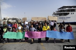 FILE - Stranded Afghan migrants take part in a march to demand the opening of European borders at the port of Piraeus, near Athens, Greece, March 8, 2016.