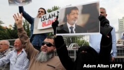 Warga membawa gambar-gambar Almarhum mantan Presiden Mesir Morsi usai shalat jenazah di Istanbul, Turki, Selasa (18/6). 
