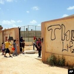 Children play outside their grafitti-covered school yard, closed for months after the uprising, Benghazi (File Photo - June 26, 2011)