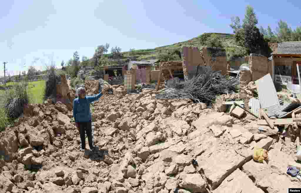 Seorang perempuan menunjuk rumahnya yang ambruk akibat gempa 6,6 Skala Richter di daerah Minxian, provinsi Gansu (22/7).