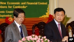 Thaksin Shinawatra, former Thai prime minister, center, sits together with Cambodian Deputy Prime Minister Sok An, left, as Thaksin gives a lecture to Cambodian economists in Phnom Penh, Cambodia, Saturday, Sept. 17, 2011. 