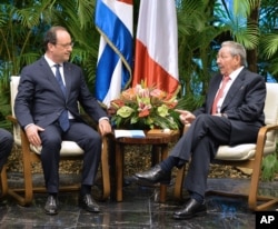 FILE - French President Francois Hollande, left, and Cuban President Raul Castro talk during a meeting at Revolution Palace in Havana, Cuba, May 11, 2015.