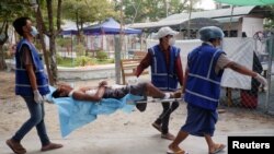Des agents de santé bénévoles portent un manifestant blessé par balle lors d'une manifestation contre le coup d'État militaire à Mandalay, Myanmar/Birmanie, le 21 mars 2021. 