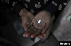 FILE - An AIDS patient in New Delhi, India, holds an anti-retroviral drug.