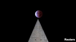 Gerhana bulan parsial terlihat di atas Washington Monument di Washington, DC Jumat dini hari (19/11). 